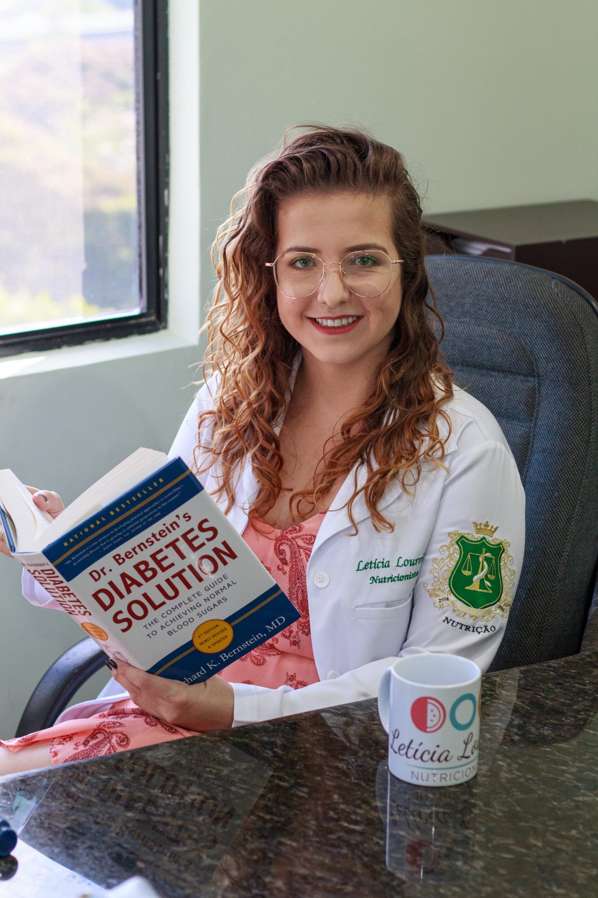 Letícia Loureiro, nutricionista e educadora em diabetes, segurando um livro sobre diabetes